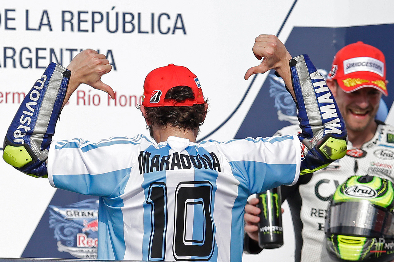 In this April 19, 2015, photo, wearing a jersey of the Argentine national soccer team with the name and number 10 of Diego Armando Maradona, Italy's Valentino Rossi celebrates on the podium after winning the MotoGP race of the Argentina's Motorcycle Grand Prix at the Termas de Rio Hondo circuit in Argentina. (AP Photo/Natacha Pisarenko)