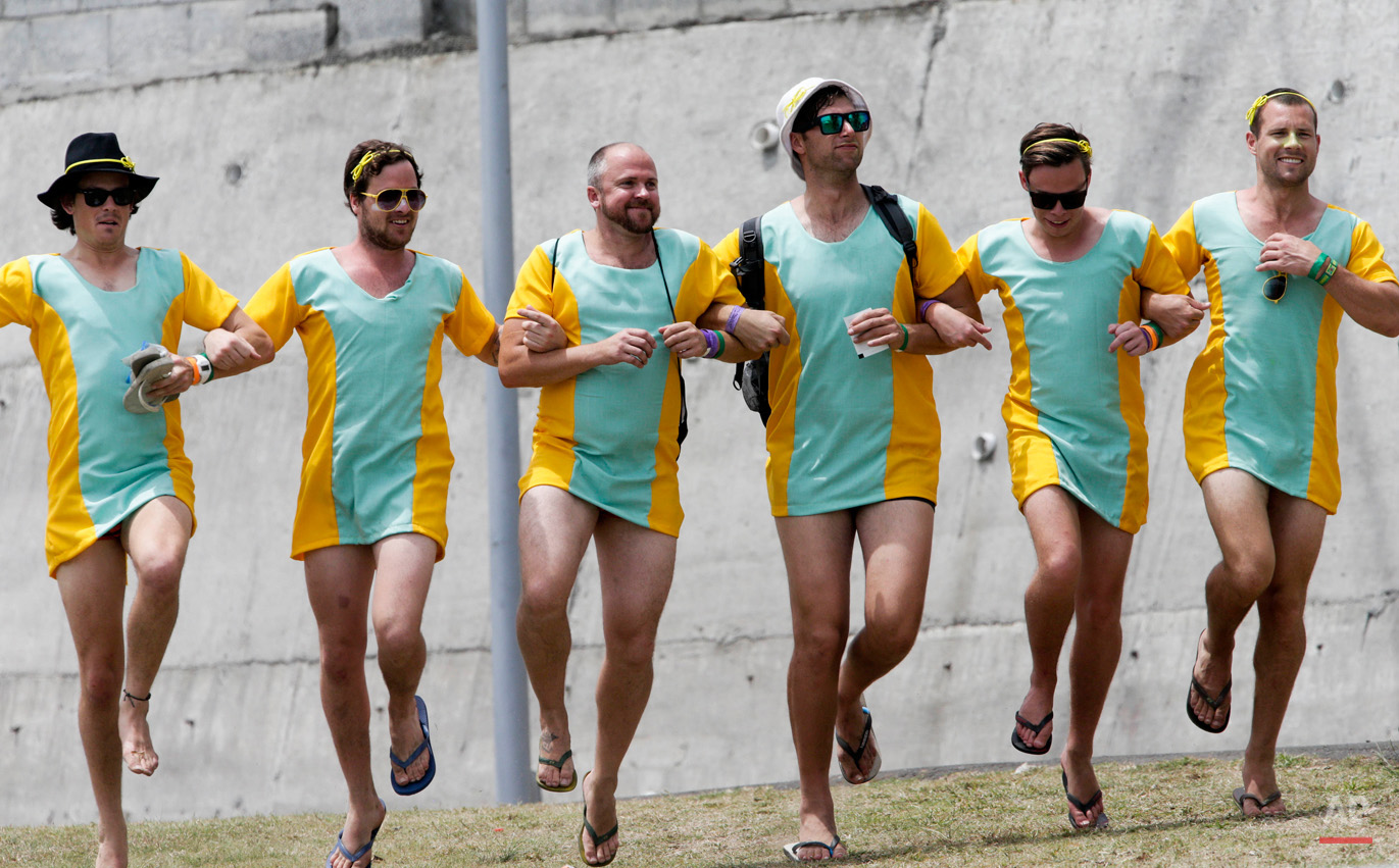 In this June 5, 2015, photo, Australian cricket fans dance arm in arm as they watch the second innings on the third day of the first cricket Test match between Australia and West Indies in Roseau, Dominica. (AP Photo/Arnulfo Franco)