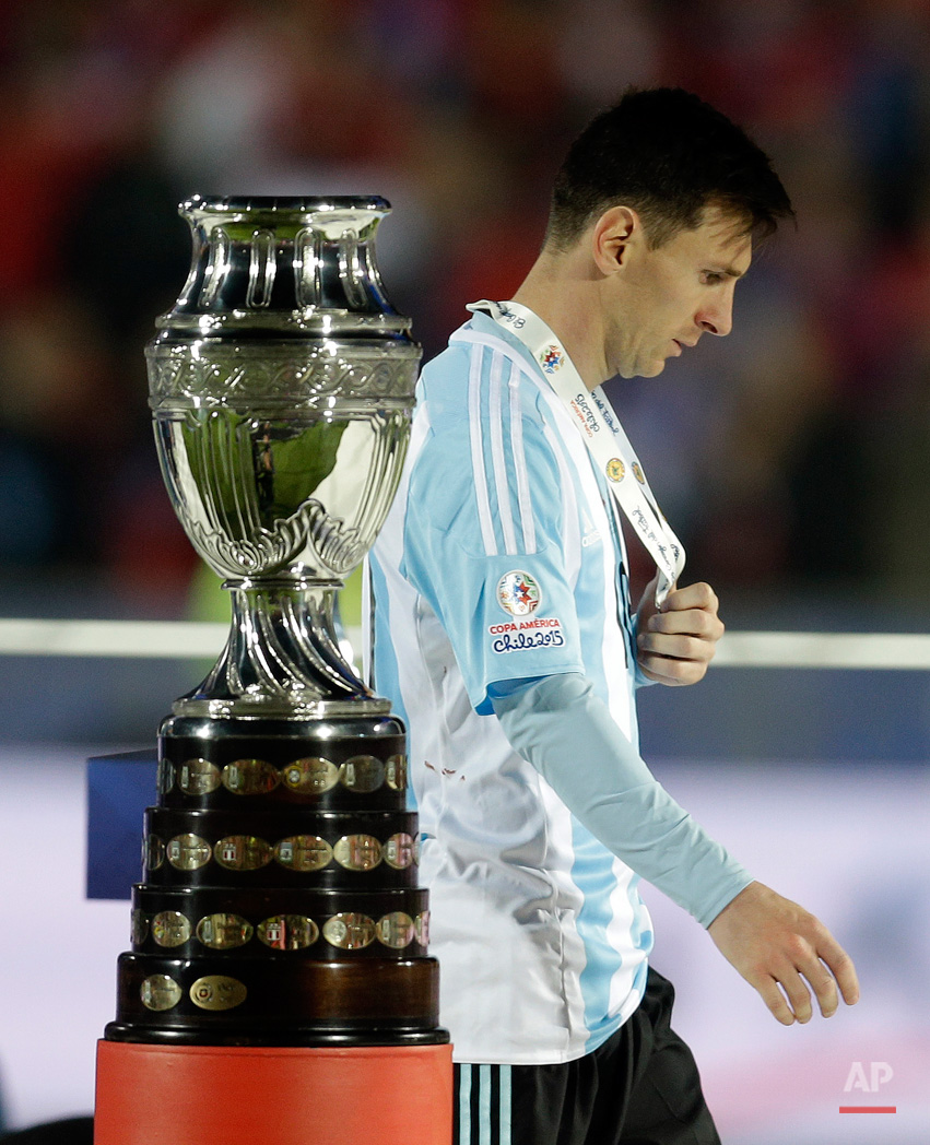 In this July 4, 2015, photo, Argentina's Lionel Messi walks by the Copa America trophy after receiving the silver medal after the final game with Chile at the National Stadium in Santiago, Chile. Chile goalkeeper Claudio Bravo made a save and striker Alexis Sanchez converted the winning penalty as host Chile defeated Argentina 4-1 in a shootout after a 0-0 draw in the Copa America final.(AP Photo/Natacha Pisarenko)