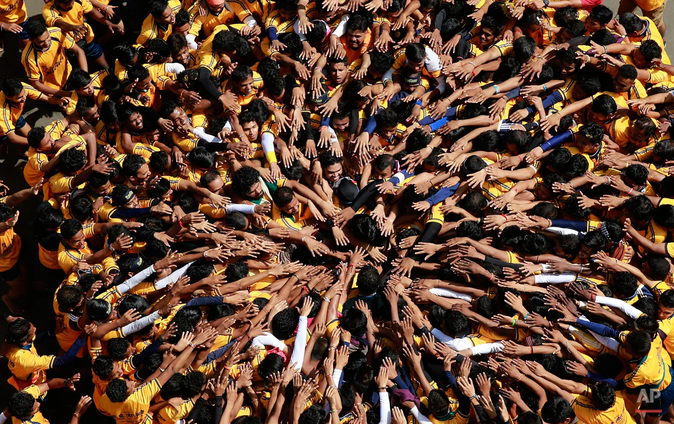 Indian youths form a human pyramid to break the "Dahi handi," an earthen pot filled with curd hanging above them, as part of celebrations to mark the Janmashtami festival in Mumbai, India, Sunday, Sept 6. 2015. The festival marks the birth of Hindu god Krishna and the act seeks to reenact the story of Lord Krishna stealing butter during his childhood. (AP Photo/Rafiq Maqbool)