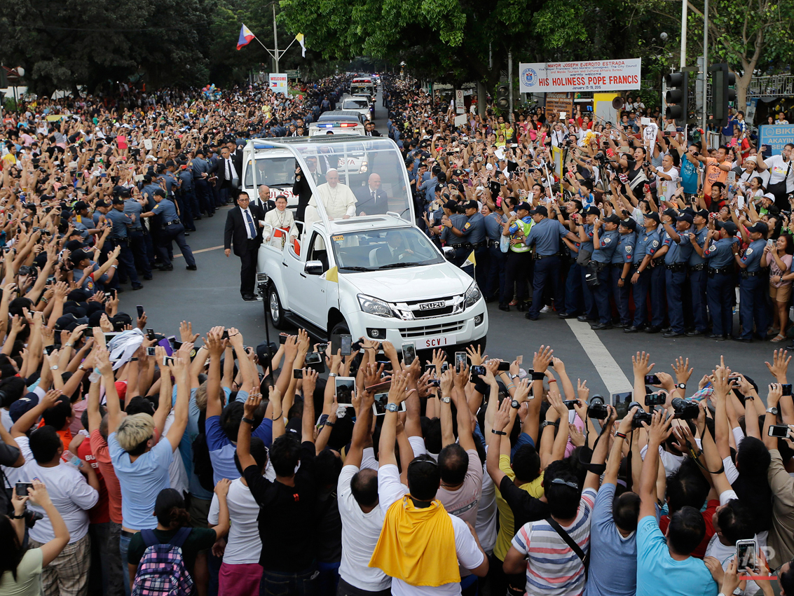  In this Friday, Jan. 16, 2015 photo, Filipino Catholics take photos, using their phones and tablets, of Pope Francis aboard his Popemobile as his motorcade passes by on the way to another "Meeting With Families" at the Mall of Asia Arena in Manila, 