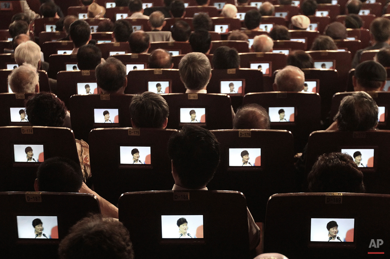  In this Saturday, Aug. 15, 2015, photo, small screens show South Korean President Park Geun-hye as participants listen to her speech during a ceremony to celebrate Korean Liberation Day from Japanese colonial rule in 1945, at Seong Cultural Center i