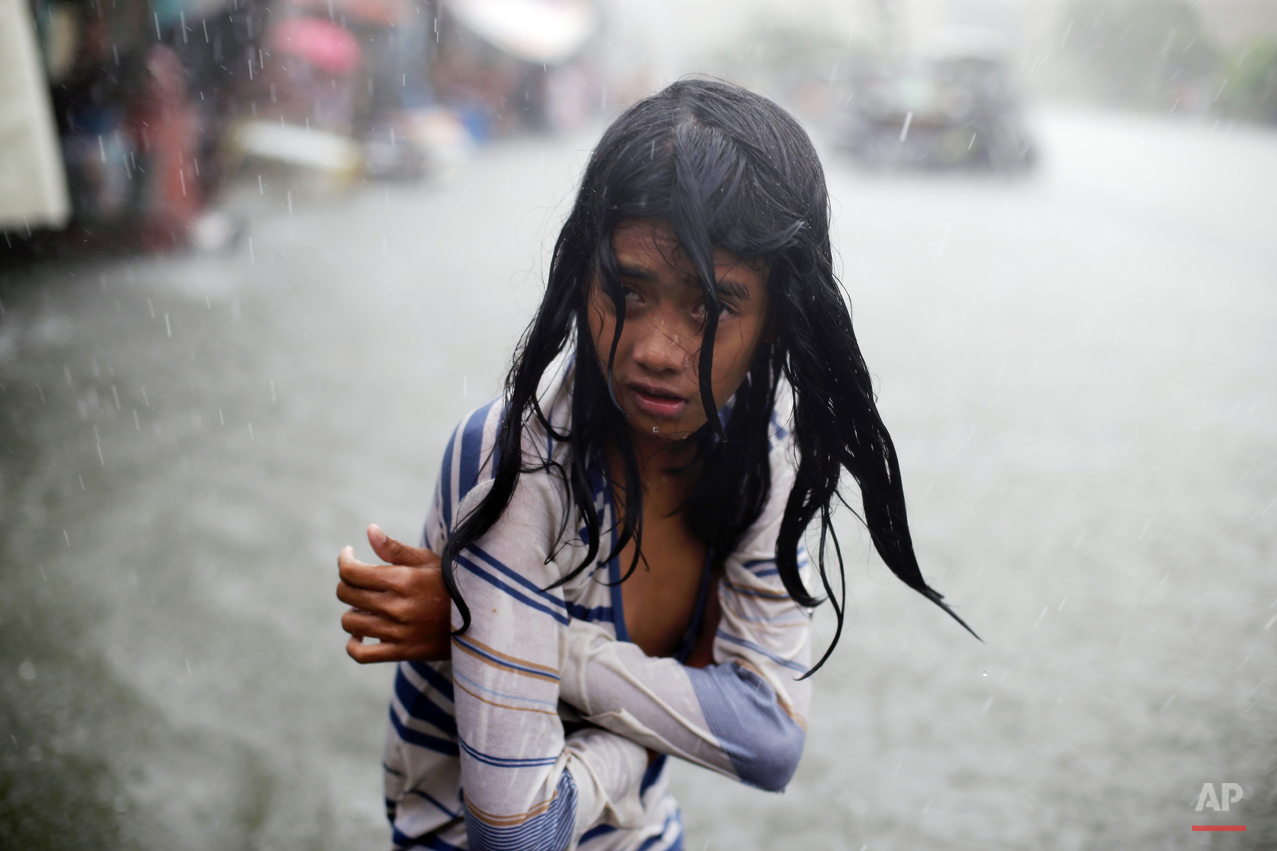  In this Wednesday, July 8, 2015, photo, a Filipino girl tries to keep herself warm as she wades through floodwaters in the coastal village of Malabon, north of Manila, Philippines. Typhoon Chan-Hom passed over the northeastern waters of the Philippi