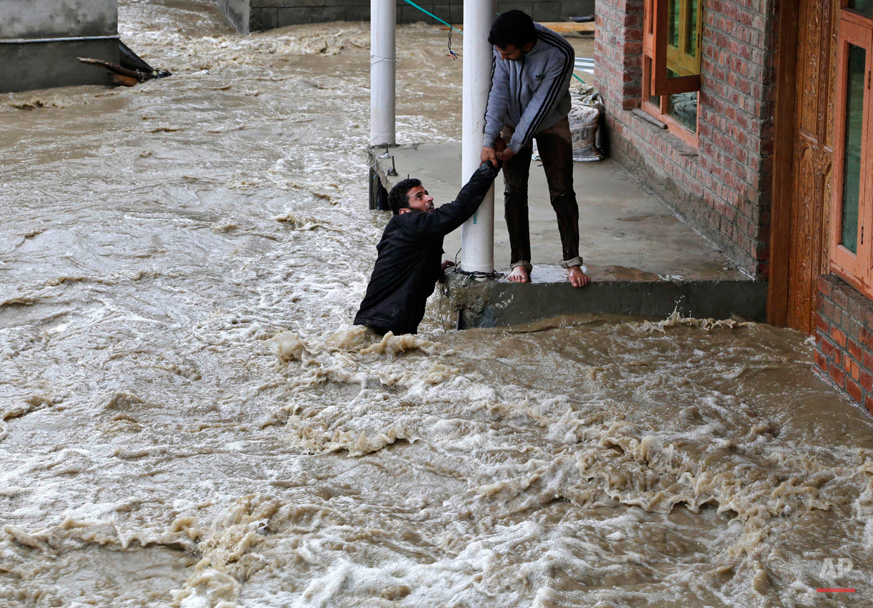  In this March 30, 2015 photo, a Kashmiri man stretches his hand to help a local evacuate from a flood affected area in Srinagar, Indian-controlled Kashmir. Hundreds of Kashmiris in both India and Pakistan moved to higher ground Monday as rain-swolle