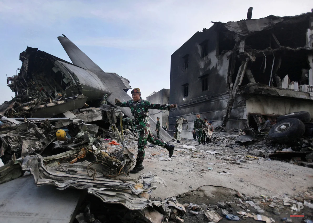 Rescuers search for victims at the site where an Indonesian air force transport plane crashed in Medan, North Sumatra, Indonesia, Wednesday, July 1, 2015. The C-130 Hercules plane crashed into a residential neighborhood in the country's third-largest city on June 30. (AP Photo/Binsar Bakkara)