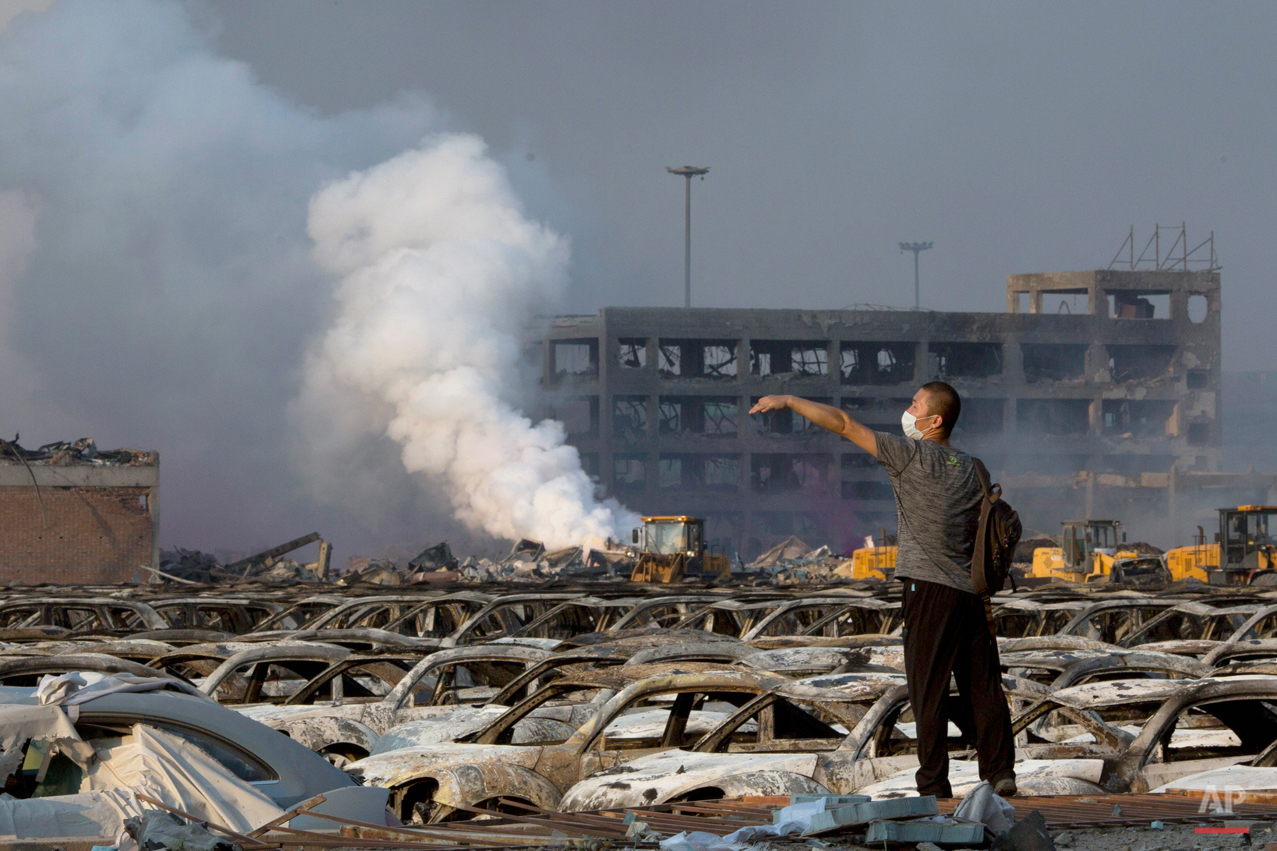  In this photo taken Thursday, Aug. 13, 2015, a man walks through the site of an explosion at a warehouse in northeastern China's Tianjin municipality. Rescuers have pulled a survivor from an industrial zone about 32 hours after it was devastated by 