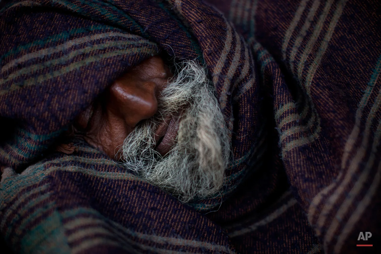 An Indian homeless man sleeps covered in a blanket early morning in the old quarters of Delhi, India, Friday, Feb. 20, 2015. (AP Photo/Bernat Armangue)