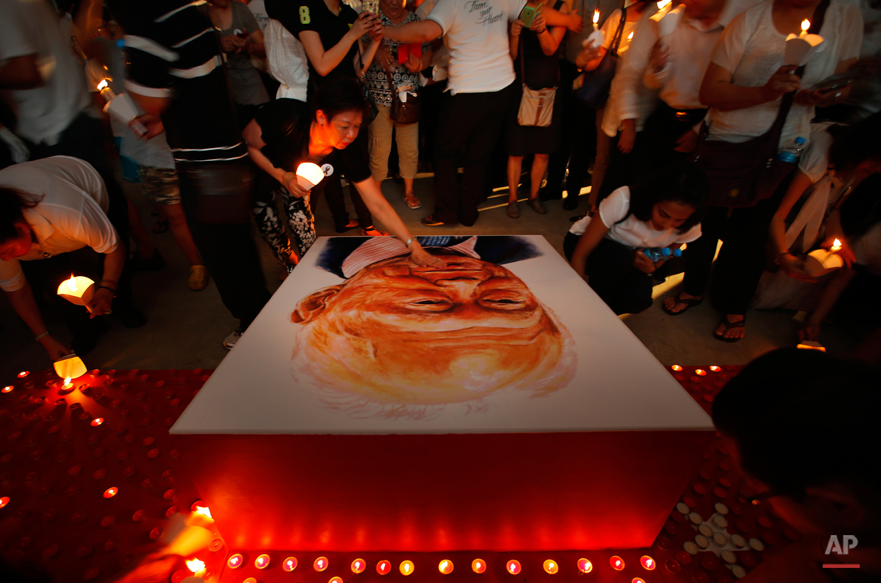  A woman touches the portrait of the late Lee Kuan Yew as others light candles as a tribute to him, Friday, March 27, 2015, in Singapore. Lee, 91, died Monday at Singapore General Hospital after more than a month of battling severe pneumonia. The gov