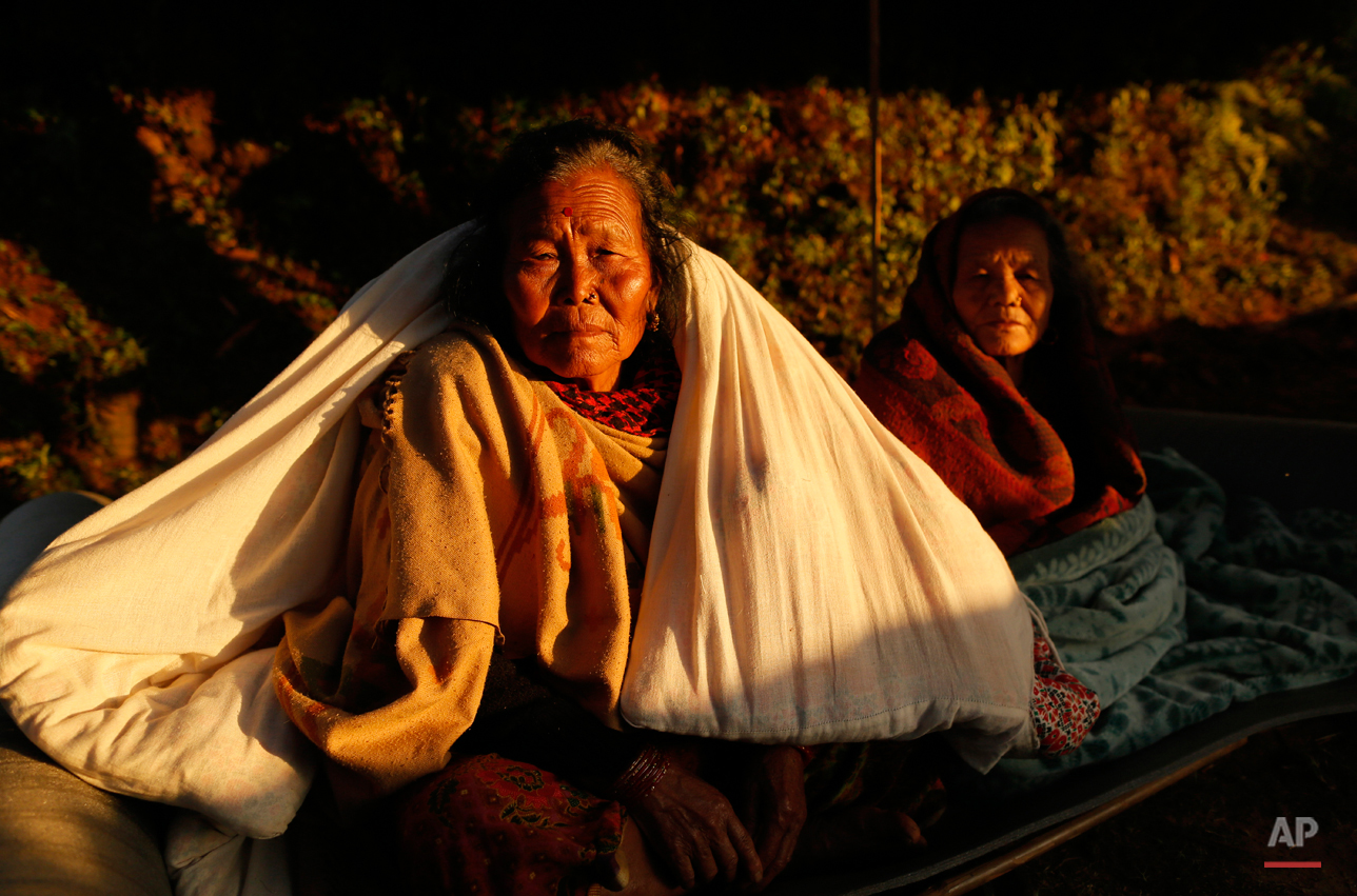  In this Tuesday, April 28, 2015, photo, two elderly women sit in the evening sun with blankets in the destroyed village of Paslang near the epicenter of Saturday's massive earthquake in the Gorkha District of Nepal. The death toll from the quake, Ne