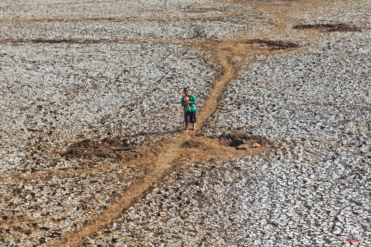 In this Saturday, Sept. 19, 2015 photo, a villager walks on a dried up dam after collecting some water in Rongkop, central Java, Indonesia. Several areas on the densely populated island of Java have been hit by drought during this dry season, forcin