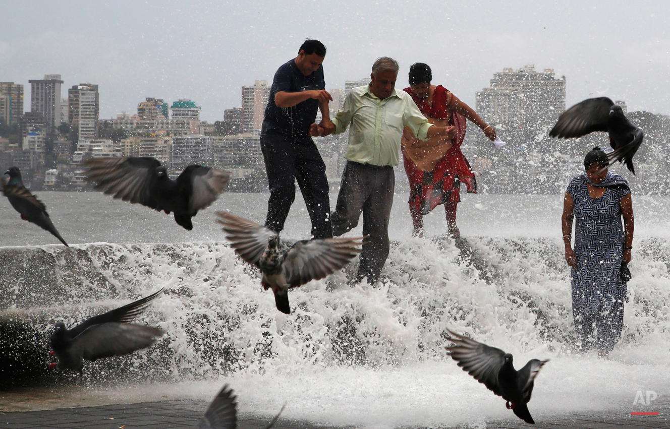  People are doused by waves crashing on the Arabian Sea shore marking the arrival of monsoon season in Mumbai, India, Tuesday, June 16, 2015. The annual rains which usually hit India from June to September are crucial for farmers whose crops feed hun