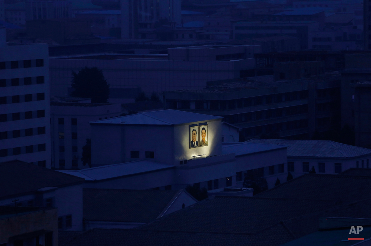  In this Aug. 19, 2015 photo, portraits of the late North Korean leaders Kim Il Sung, left, and Kim Jong Il glow on the facade of a building among others at dawn in Pyongyang, North Korea. (AP Photo/Dita Alangkara) 