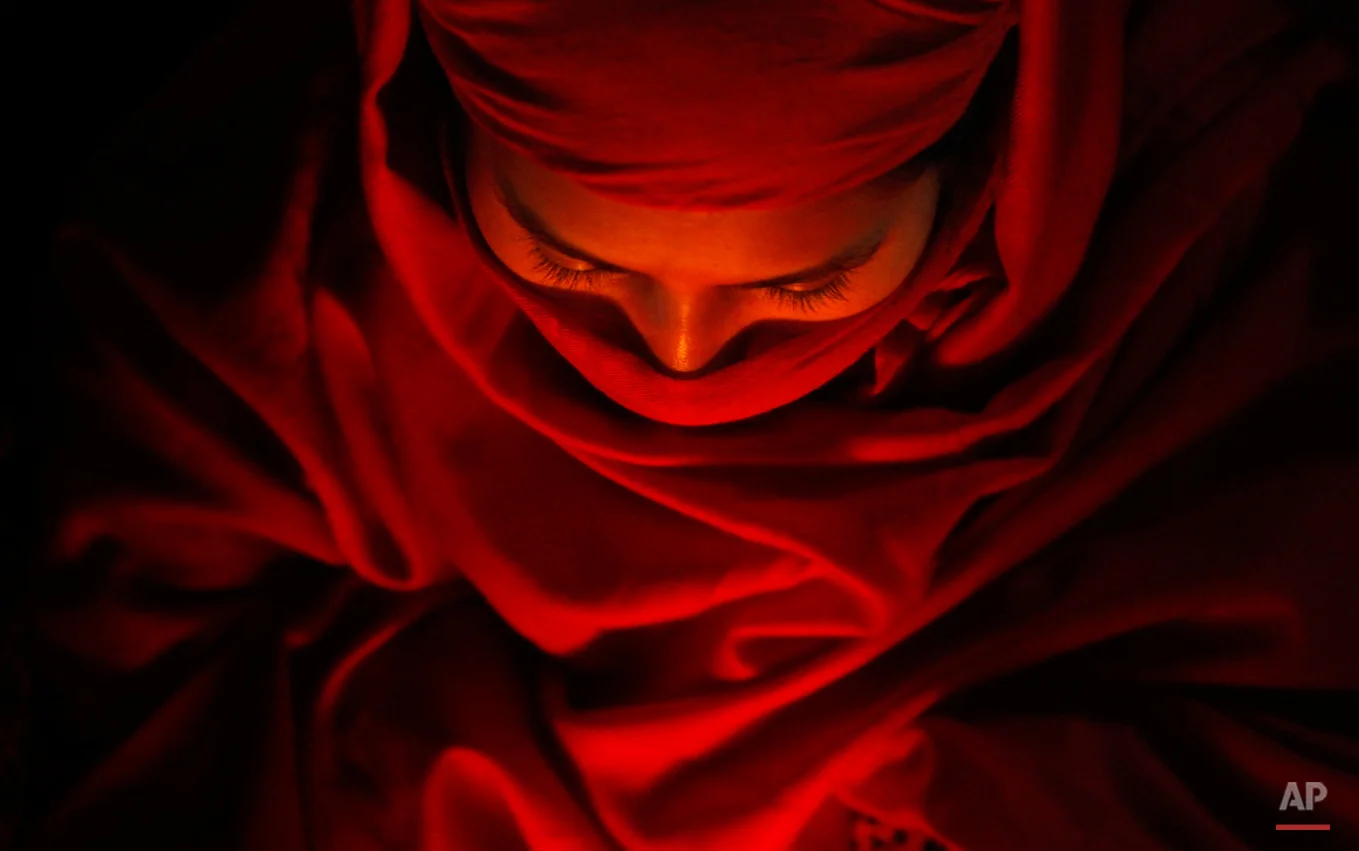 In this Monday, Jan. 5, 2015 photo, a Nepalese woman devotee sits near a bon fire to warm herself before she takes a holy dip in Salinadi River during the first day of month long Swasthani Bratakatha festival in Sankhu, on the outskirts of Katmandu. During this month-long festival, devotees recite Holy Scriptures dedicated to Hindu goddess Swasthani and Lord Shiva. Unmarried women pray to get a good husband while those married pray for the longevity of their husbands by observing a month-long fast. (AP Photo/Niranjan Shrestha)