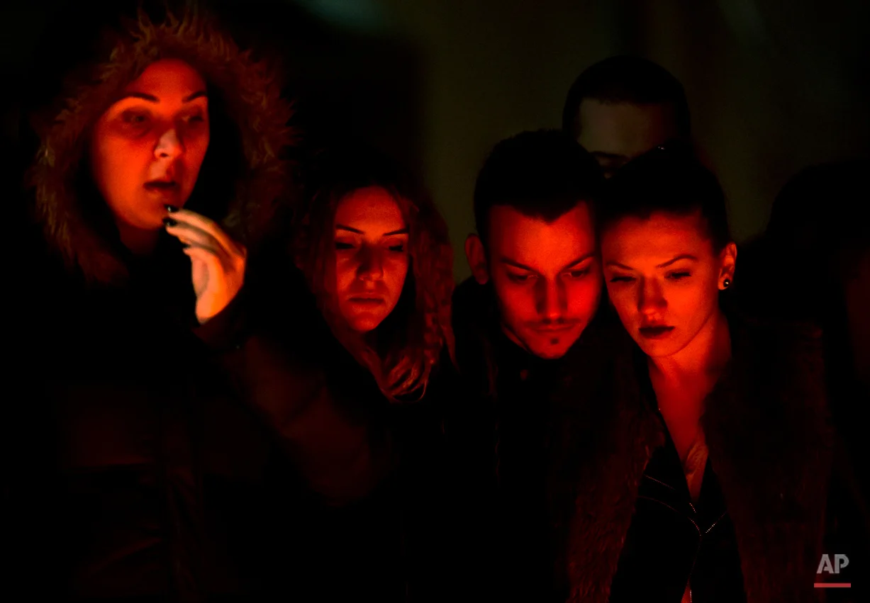  People, lit by burning candles, stand outside the compound that housed a nightclub where a fire occurred in the early Saturday in Bucharest, Romania, to pay respects to the victims, 24 hours after the accident Sunday, Nov. 1, 2015. Flames spread qui