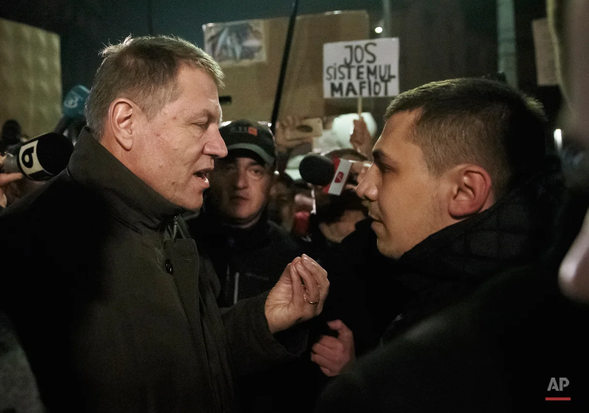  Romanian President Klaus Iohannis speaks to a protester in University Square, the staging area for protests calling for better governance and an end to corruption, in Bucharest, Romania, Sunday night, Nov. 8, 2015. People power has ousted the Romani