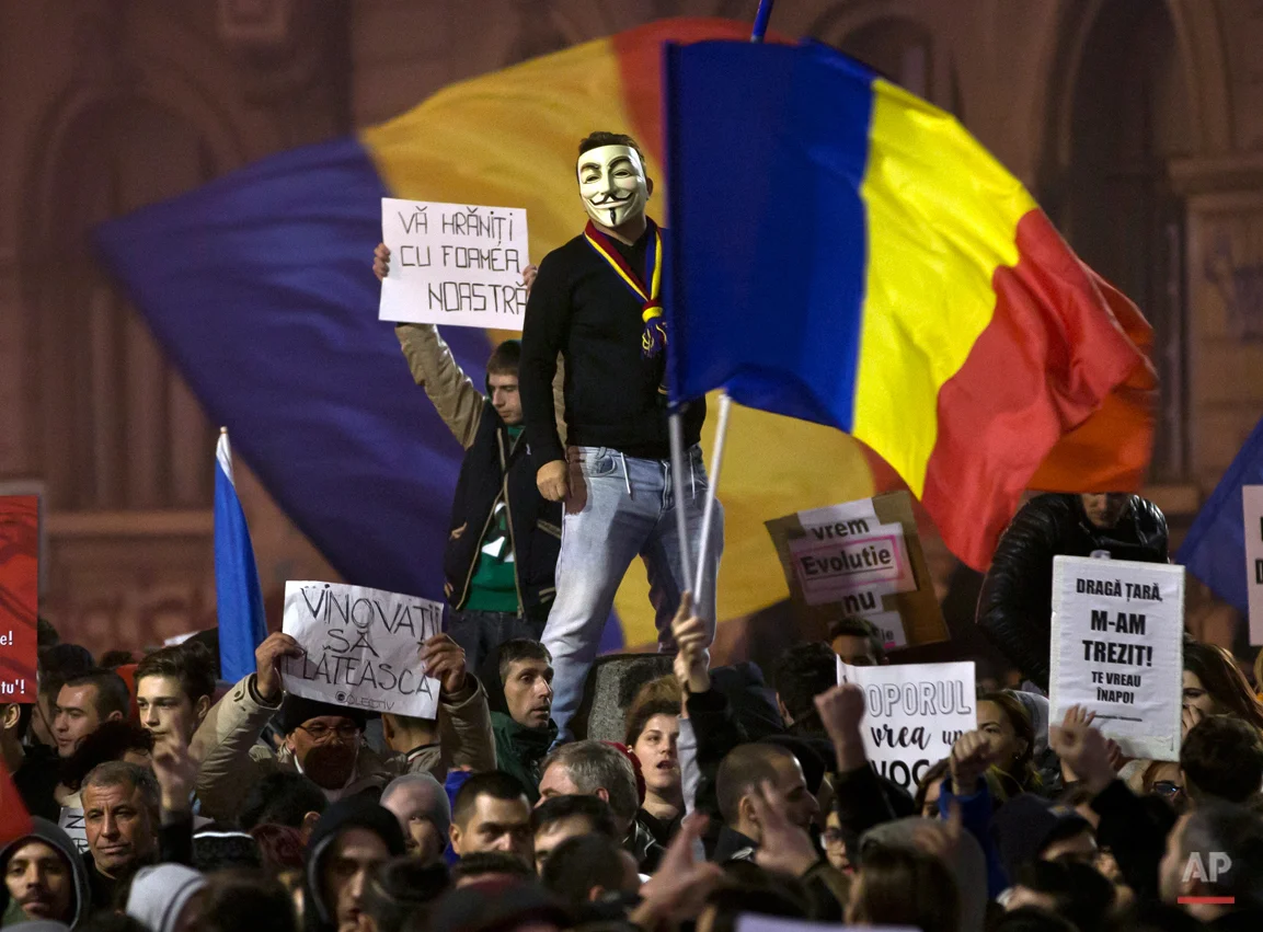  A man wearing a Guy Fawkes mask stands above protesters shouting slogans against the Romanian politicians during the fourth day of protests, joined by tens of thousands across the country, calling for early elections, in Bucharest, Romania, Friday, 