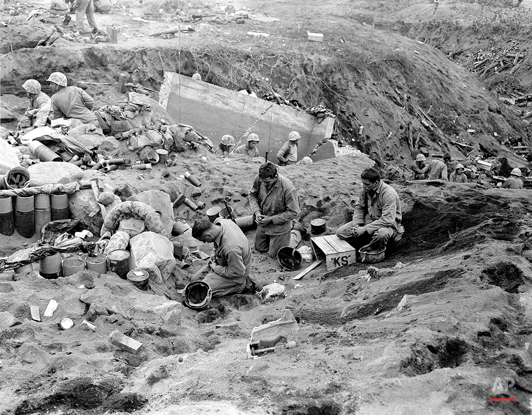  U.S. Marines kneel in prayer before they receive communion during a pause in the fighting for Motoyam Airstrip No. 1 on Iwo Jima, Volcano Island of Japan, March 1, 1945 in World War II.  The soldiers, from left are , Pfc. Edmond L. Fadel, Niagara Fa