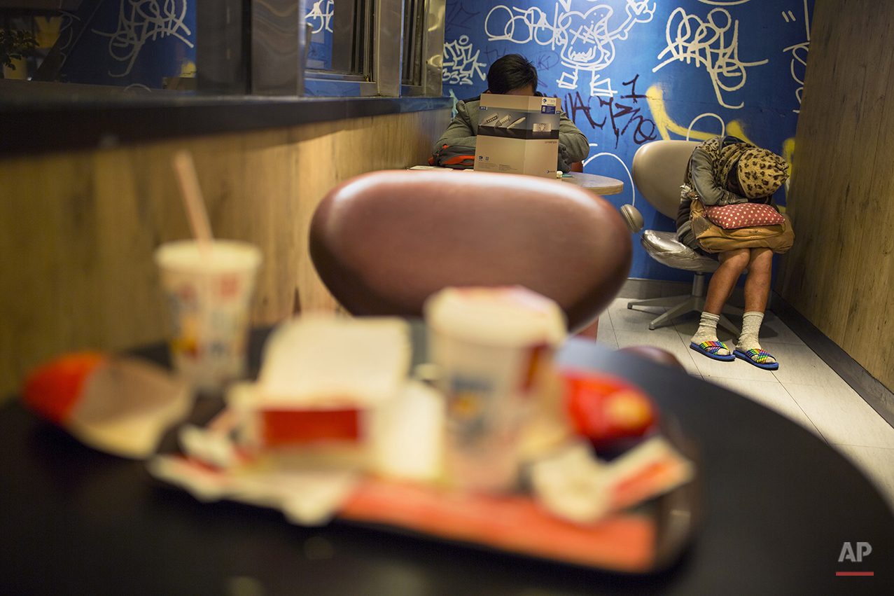  In this Oct. 29, 2015 photo, a woman sleeps with her belongings at night in a 24-hour McDonald’s branch in Hong Kong. The recent death of a woman at a Hong Kong McDonald’s, where her body lay slumped at a table for hours unnoticed by other diners, h