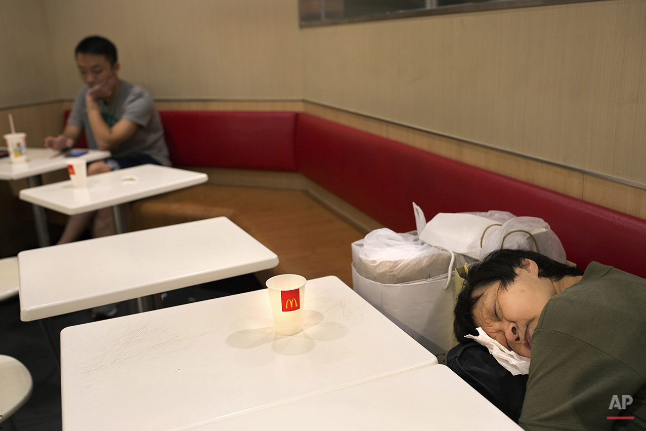  In this Oct. 30, 2015 photo, a woman sleeps with her belongings at night in a 24-hour McDonald’s branch in Hong Kong. The recent death of a woman at a Hong Kong McDonald’s, where her body lay slumped at a table for hours unnoticed by other diners, h
