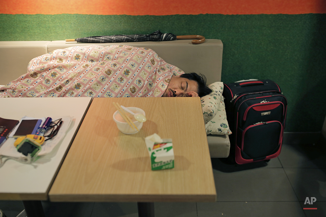  In this Nov. 9, 2015 photo, a man sleeps with his belongings at night in a 24-hour McDonald’s branch at night in Hong Kong. The recent death of a woman at a Hong Kong McDonald’s, where her body lay slumped at a table for hours unnoticed by other din