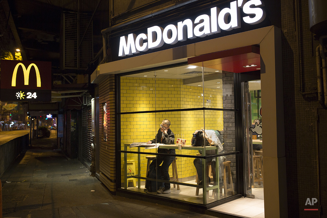  In this Oct. 29, 2015 photo, two men sleep with their belongings at night in a 24-hour McDonald’s branch in Hong Kong. The recent death of a woman at a Hong Kong McDonald’s, where her body lay slumped at a table for hours unnoticed by other diners, 