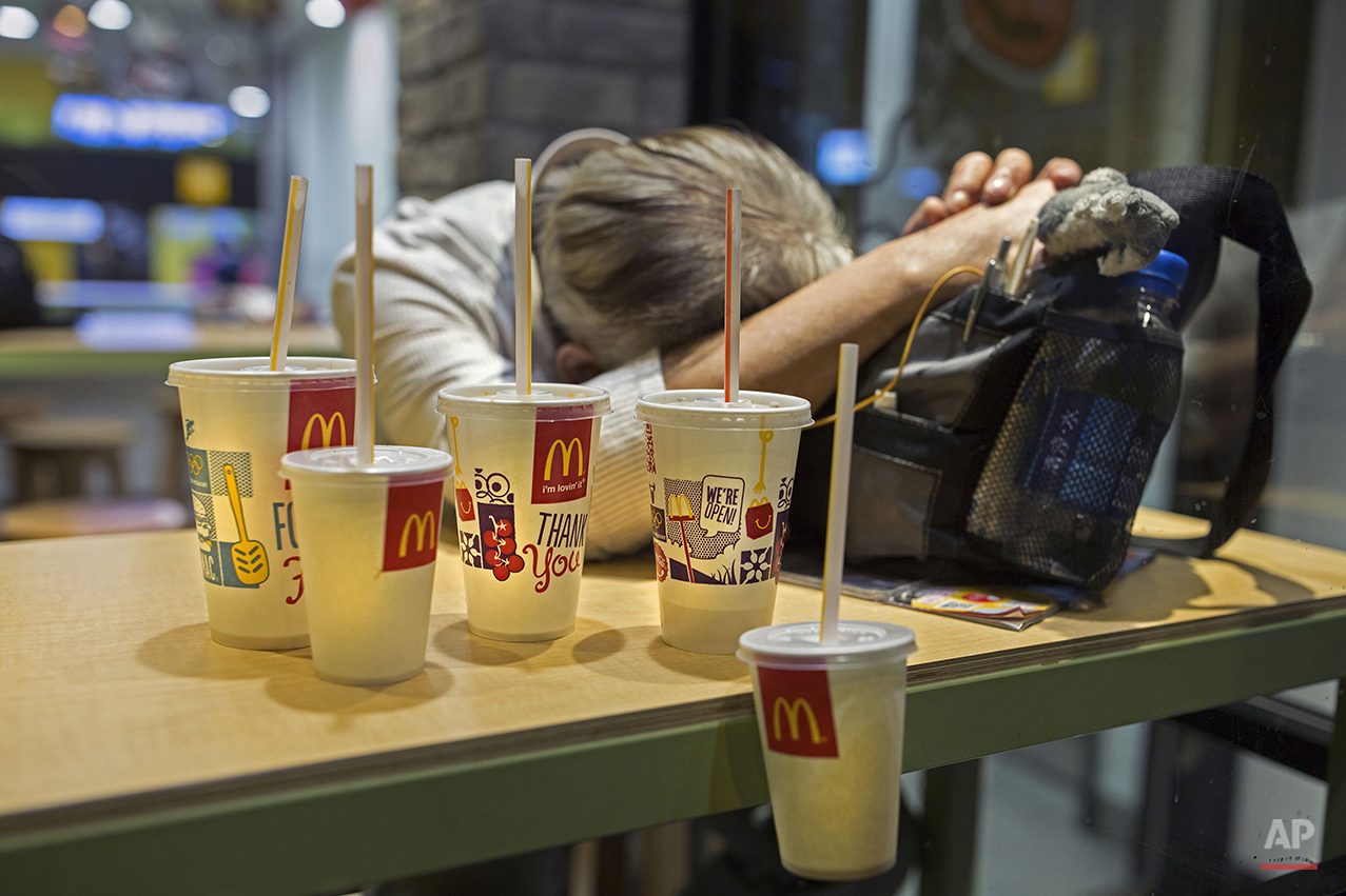  In this Oct. 29, 2015 photo, a man sleeps with his belongings at night in a 24-hour McDonald’s branch in Hong Kong. The recent death of a woman at a Hong Kong McDonald’s, where her body lay slumped at a table for hours unnoticed by other diners, has
