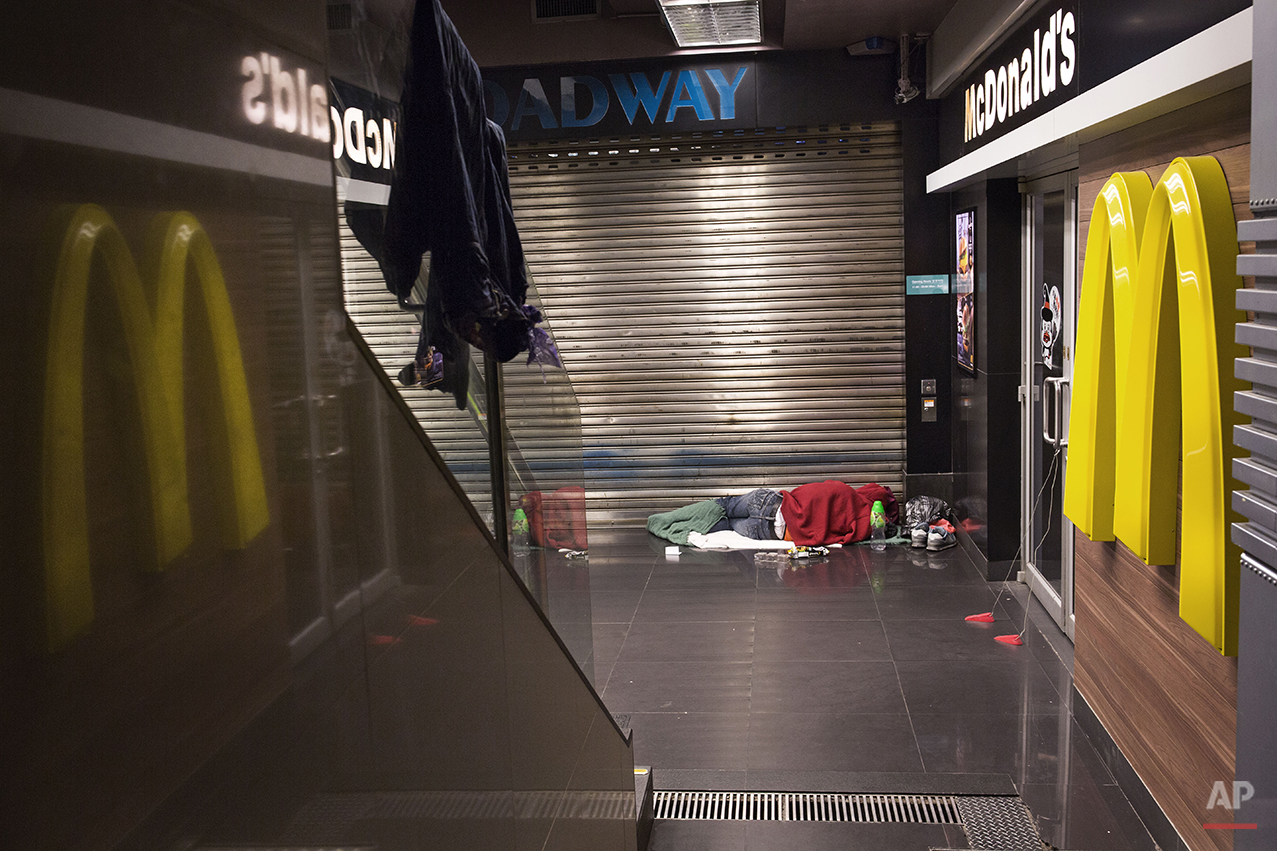  In this Nov. 5, 2015 photo, a man sleeps with his belongings at night outside a 24-hour McDonald’s branch in Hong Kong. The recent death of a woman at a Hong Kong McDonald’s, where her body lay slumped at a table for hours unnoticed by other diners,