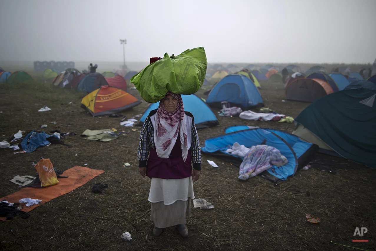 In this photo taken on Saturday, Sept. 12, 2015, Syrian refugee Sabha Nasser, 62, who came from al-Hasaka, Syria, carries her belongings on her head as poses for a picture, after crossing the Serbian-Hungarian border near Roszke, southern Hungary. “We had to flee our homes, the shelling is endless. I am old and I need peace. These last 15 days on the road were so humiliating and so miserable I just hope tomorrow will be better," she said. (AP Photo/Muhammed Muheisen)