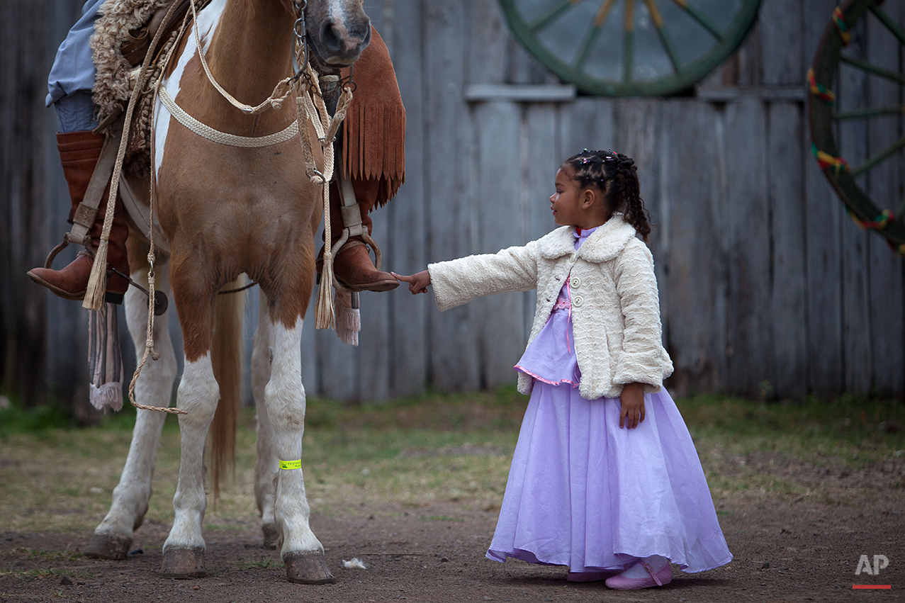  In this Sept. 20, 2015 photo, girl Alessandra Fortes de Lima, 6, touches the boot of her father Adimir Goncalves de Lima, 49, before a parade during the Semana Farroupilha or “Ragamuffin” week, in Alegrete municipality, Rio Grande do Sul state, Braz