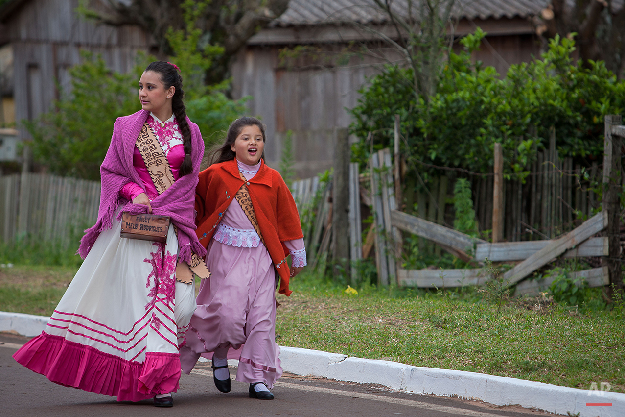  In this Sept. 19, 2015 photo, girls called "Prendas", wear gauchos clothes during the Semana Farroupilha or “Ragamuffin” week, in Alegrete municipality, Rio Grande do Sul state, Brazil. Some of the Brazilian cowboys ride with little girls wearing ol