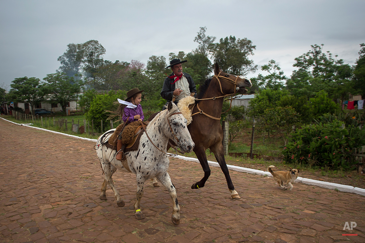  In this Sept. 19, 2015 photo, a girl and her grandfather ride their horses before a parade during the Semana Farroupilha or “Ragamuffin” week, in Alegrete municipality, Rio Grande do Sul state, Brazil. Some of the Brazilian cowboys ride with little 