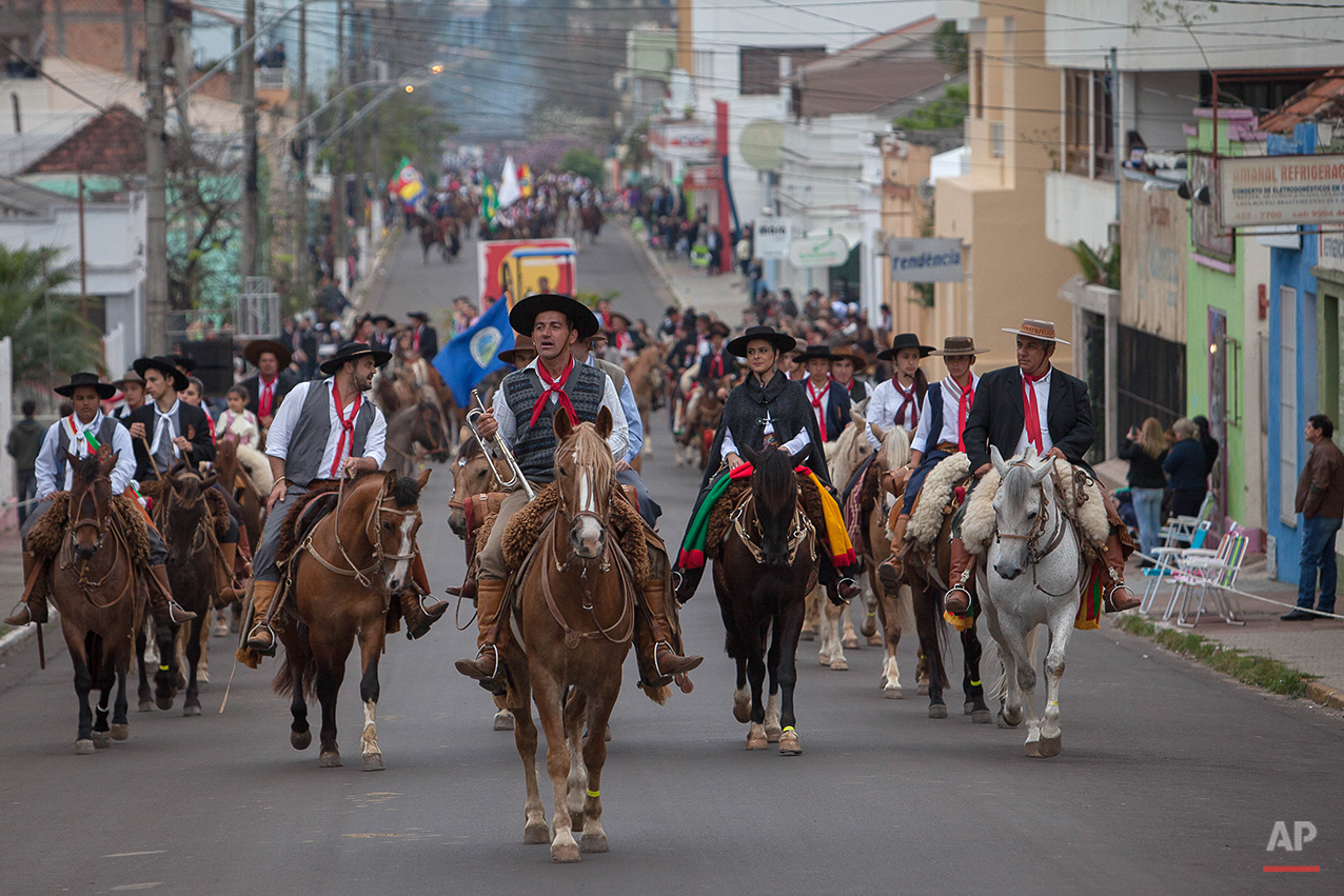  In this Sept. 20, 2015 photo, gauchos parade during the Semana Farroupilha or “Ragamuffin” week, downtown in Alegrete municipality, Rio Grande do Sul state, Brazil. Wearing traditional broad-brimmed hats and red neckerchiefs, their trousers tucked i