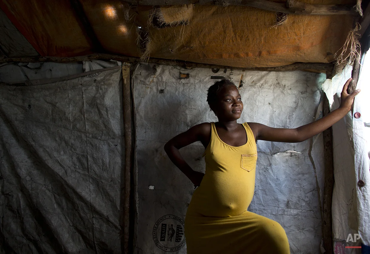  In this June 26, 2015 photo, Mirlande Senate, 17 and eight-months pregnant, stands in the small makeshift shelter where she lives alone in a Cite Soleil tent camp set up for people displaced by the 2010 earthquake in Port-au-Prince, Haiti. Orphaned 