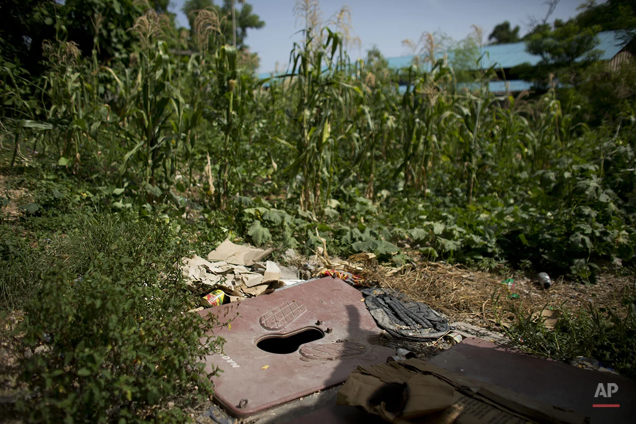  In this June 29, 2015 photo, a makeshift squat toilet installed over a shallow pit serves families living in and around damaged buildings behind the ruins of the National Theater, in central Port-au-Prince, Haiti. Sanititation is a problem in camps 