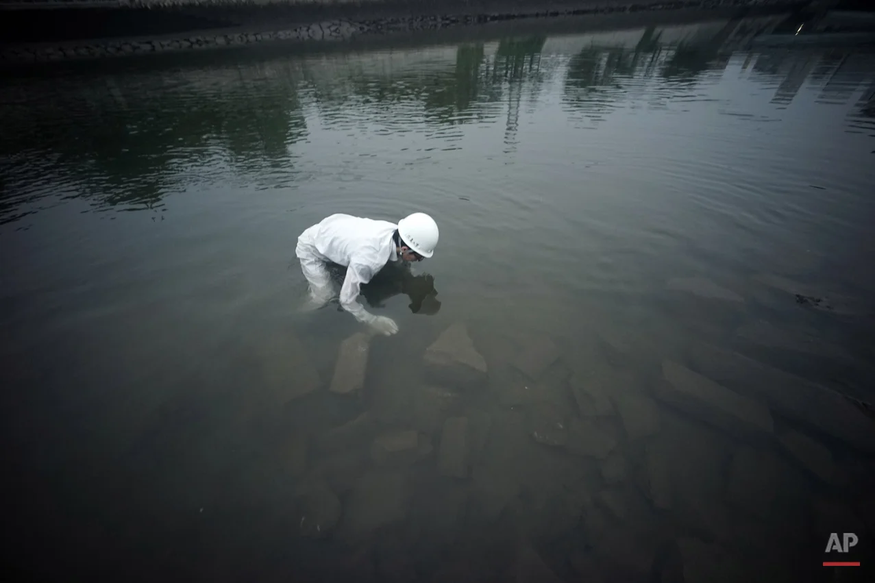  In this July 4, 2015 photo, Rebun Kayo, Hiroshima University graduate student, finds debris from the Atomic Bomb Dome, as it is known today  in the river in Hiroshima, Hiroshima Prefecture, southern Japan. Kayo has retrieved shattered bricks and sto