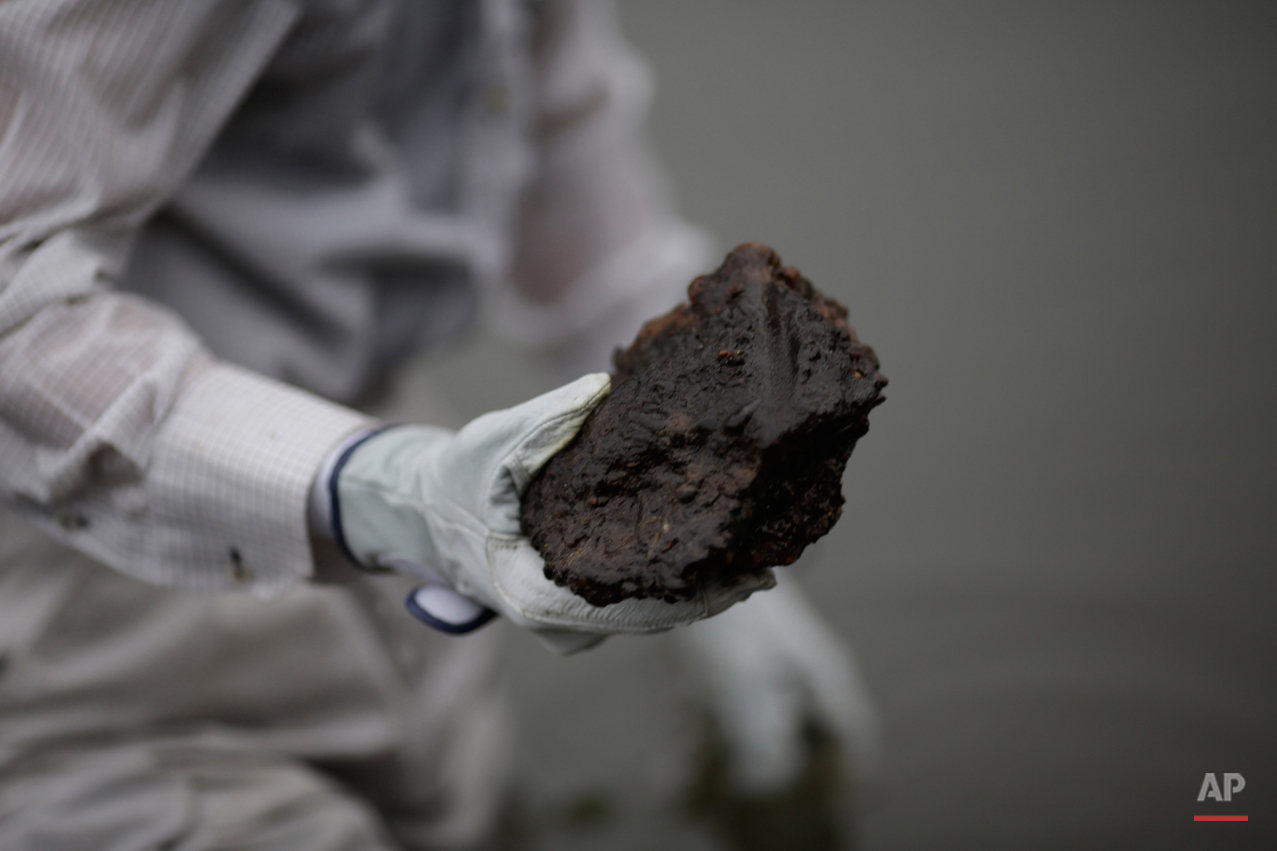  In this July 4, 2015 photo, Rebun Kayo, Hiroshima University graduate student, finds debris from the Atomic Bomb Dome, as it is known today in the river in Hiroshima, Hiroshima Prefecture, southern Japan. Kayo has retrieved shattered bricks and ston