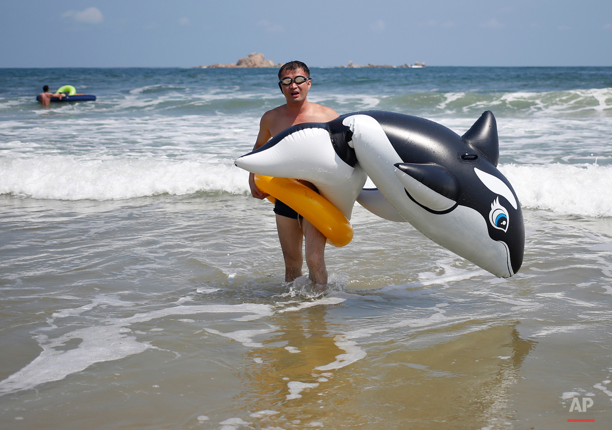  A man walks with an inflatable orca at Sijung Ho beach in North Korea, Tuesday, Aug. 18, 2015. The beach is a popular tourist destination for locals and foreigners alike. (AP Photo/Dita Alangkara) 