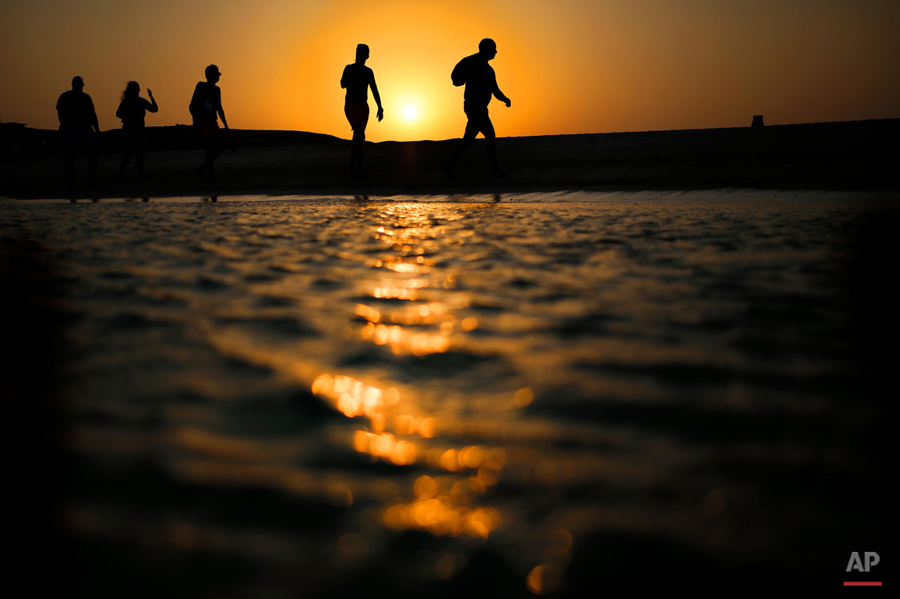  In this picture taken Thursday, Aug. 20, 2015, tourists walk on the Giftun Island beach as the sun sets over the Red Sea in Hurghada, Egypt. (AP Photo/Hassan Ammar) 