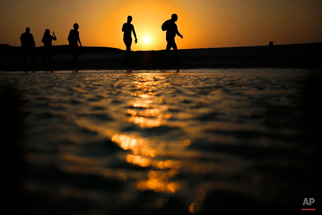 In this picture taken Thursday, Aug. 20, 2015, tourists walk on the Giftun Island beach as the sun sets over the Red Sea in Hurghada, Egypt. (AP Photo/Hassan Ammar)