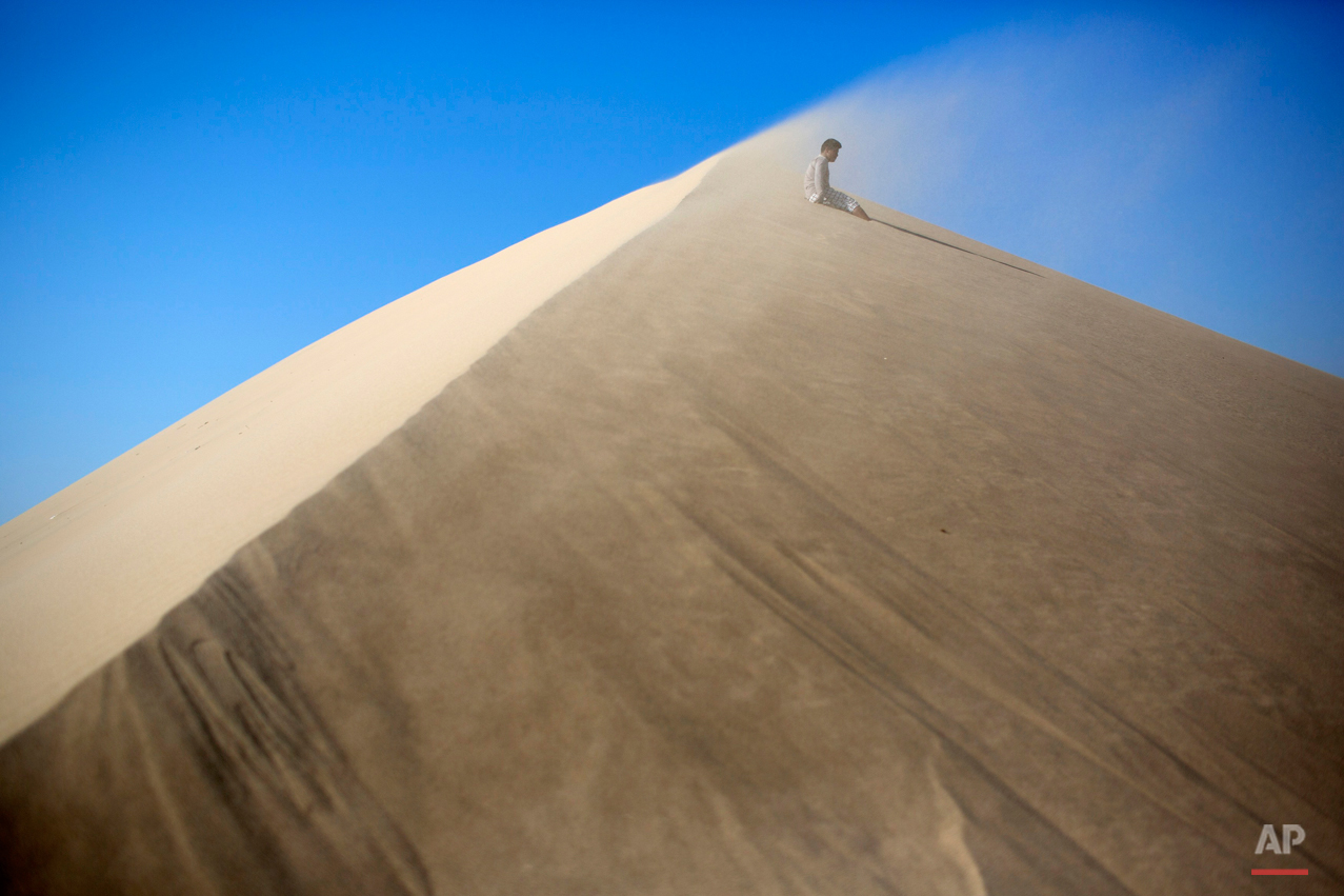  Luis Enrique Tuanama, 17, rests while climbing the Cerro de Saraja , a mountain of sand, in Ica, Peru, Friday, Aug. 7, 2015. (AP Photo/Rodrigo Abd) 