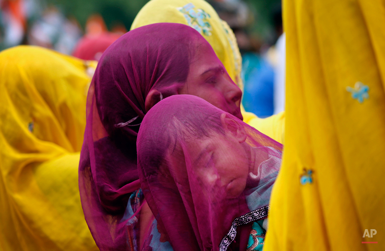  An Indian village woman covers a sleeping child with her veil as she carries him on her shoulder at Ajmer in Indiaís Rajasthan state, Wednesday, Aug. 5, 2015. Married Hindu women in parts of Indian states observe a veil, or cover their heads as a lo