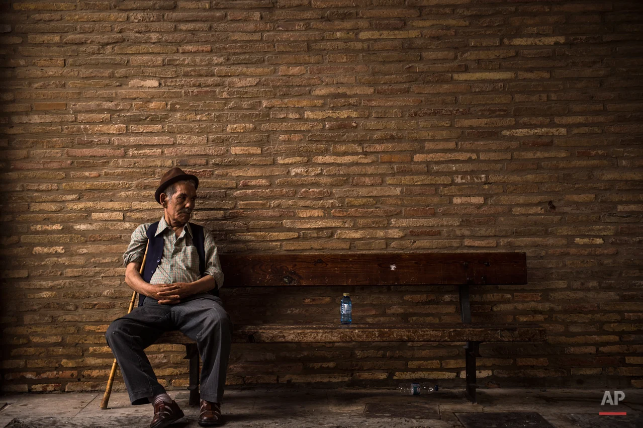 A man rests sitting on a bench next to a bottle of water, in the small village of Arguedas, northern Spain, Thursday, Aug. 6, 2015. (AP Photo/Alvaro Barrientos)