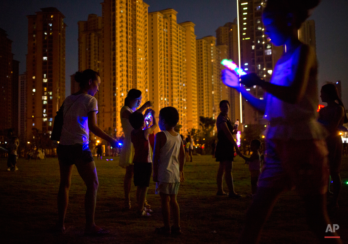  People play with illuminated toys in a public park in Wuhan in central China's Hubei province Friday, Aug. 7, 2015. Wuhan is known in China as one of the "Three Furnaces", cities notorious for their summer heat and humidity, and residents often wait