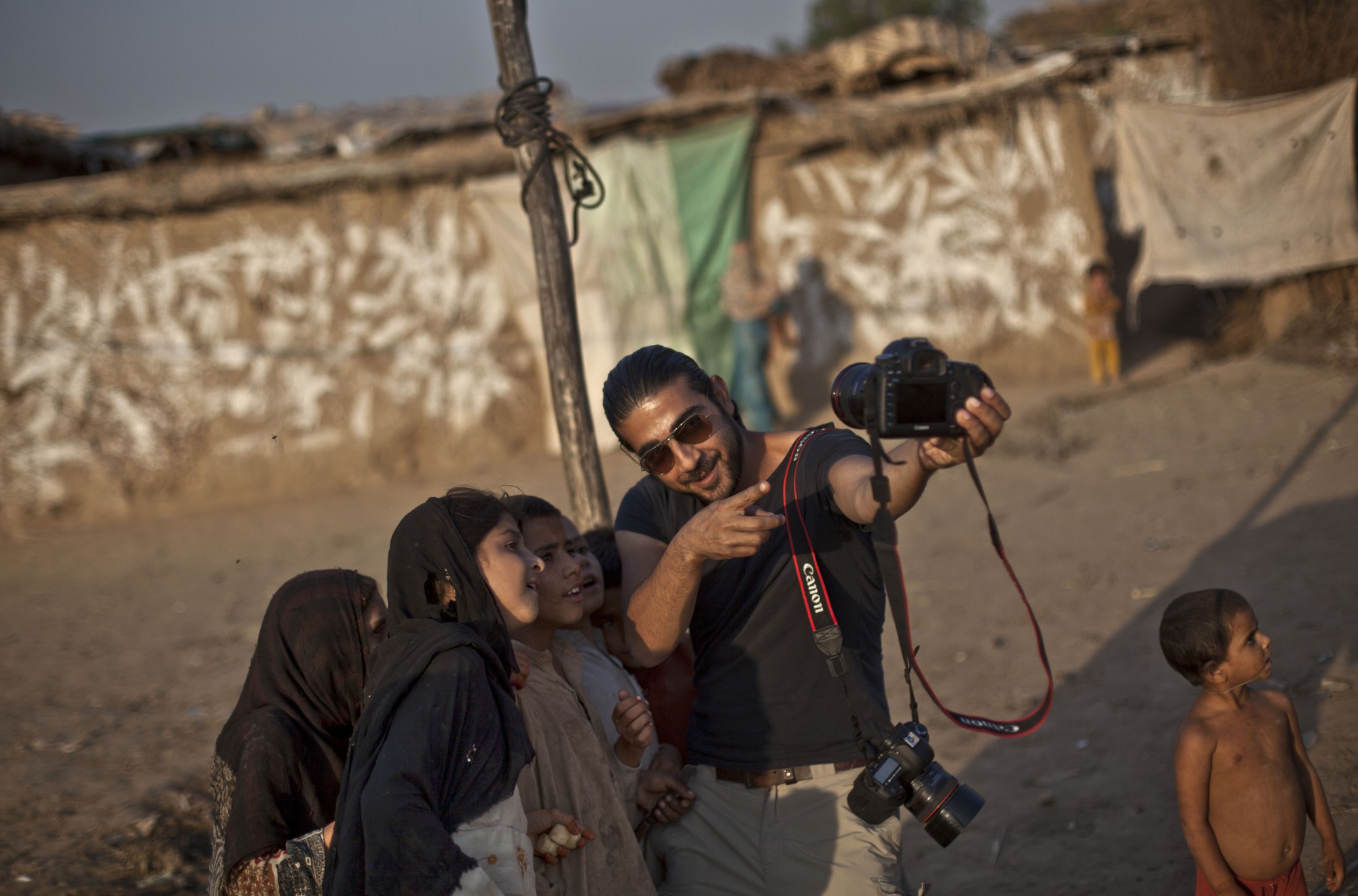  Pakistan's Chief Photographer Muhammed Muheisen shows Afghan refugee children how the camera works, in a poor neighborhood on the outskirts of Islamabad, Pakistan, Monday, Oct. 21, 2013. (AP Photo/Nathalie Bardou) 