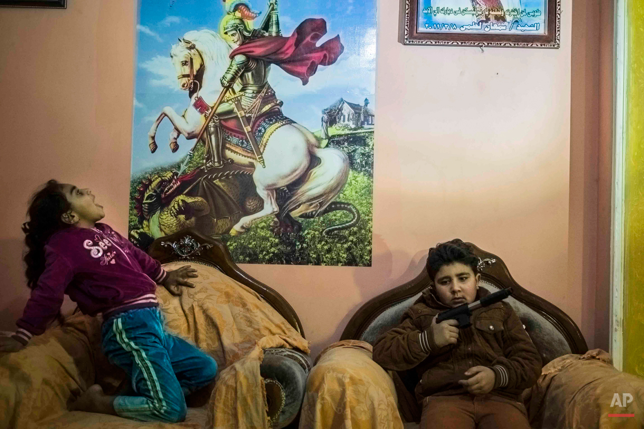  In this picture taken on Feb. 2, 2015, 10-year-old Abanoub Samaan Nazmy, right, holds a toy gun as he plays with his sister in the living room of their home in the Manshiet Nasr neighborhood of Cairo, Egypt. Abanoub, who is a Coptic Christian, lost 
