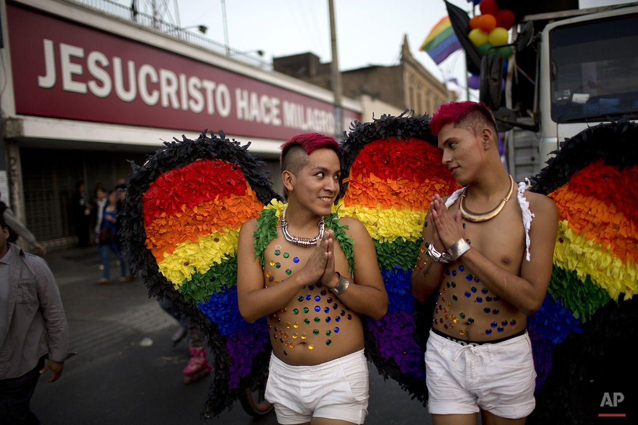  Two young men wearing rainbow colored wings march in the annual gay pride parade, past an evangelical church with a sign that reads in Spanish, "Jesus Christ does miracles," in Lima, Peru, Saturday, June 27, 2015. (AP Photo/Rodrigo Abd) 