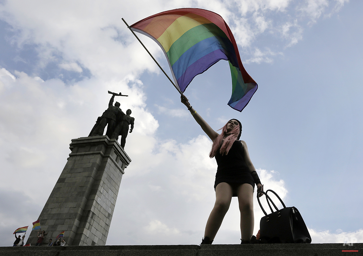  An activist waves a rainbow flag in front of the Monument of the Soviet Army, during the Sofia Gay Pride Parade in Sofia, Saturday, June  27, 2015. Hundreds paraded through the Bulgarian capital of Sofia under rainbow-colored balloons and banners fo
