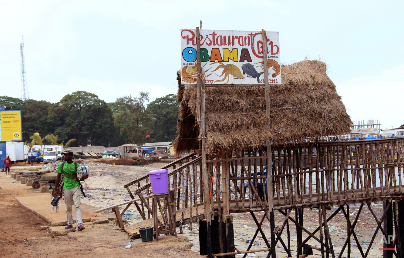  In this photo taken on Saturday, June 13, 2015, a street vendor walks past the Obama restaurant in Conakry, Guinea. Barack Obama, the United Statesí first African-American president, has captured the imagination of people across the continent where 