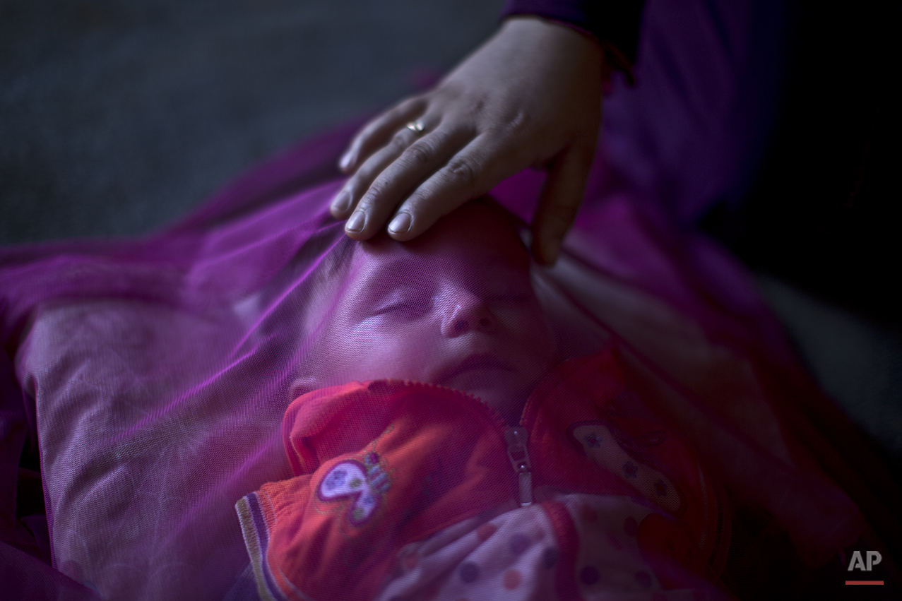  In this Tuesday, July 21, 2015 photo, Syrian refugee Kutana al-Hamadi, 24, tends to her son Almunzir, 7 months, covered with a mosquito net, whom she claims is suffering from malnutrition, at their tent in an informal tented settlement near the Syri