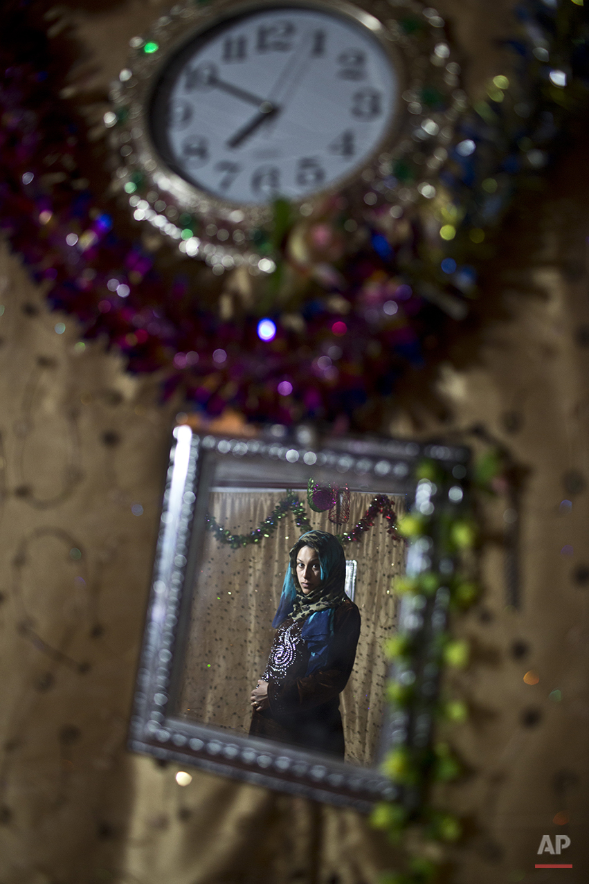  In this Saturday, July 25, 2015 photo, pregnant Syrian refugee Huda Alsayil, 20, who passed her 9th month of pregnancy, is reflected in a mirror while posing for a portrait inside her tent at an informal tented settlement near the Syrian border on t